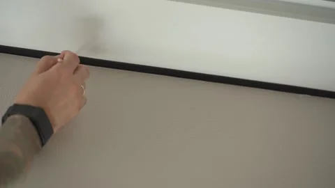 The man is touching up the chips on the wallpaper with a paintbrush. Vídeos de archivo 346547001