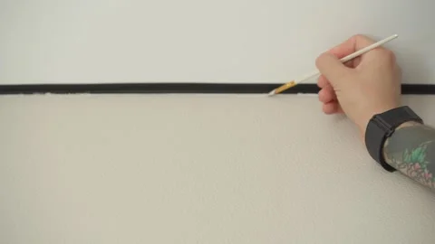 The man is touching up the chips on the wallpaper with a paintbrush. Vídeos de archivo 346547041