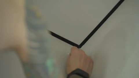 The man is touching up the chips on the wallpaper with a paintbrush. Vídeos de archivo 346547119