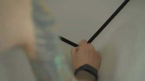 The man is touching up the chips on the wallpaper with a paintbrush. Vídeos de archivo 346547122