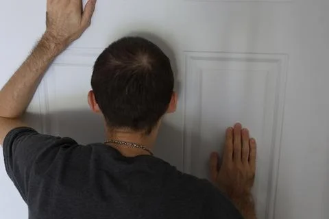 Man touching closed door with both hands back view home security concept Foto stock