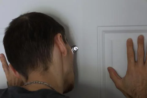 Man touching door while looking through peephole security concept 写真素材