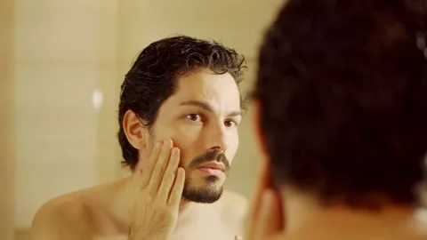 Man touching face and skin and looking at mirror at home bathroom Stock Footage 168623267