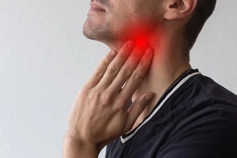 Man touching his neck, having a throat irritation on grey background Stock Photos
