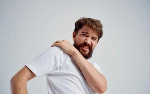 Man touching shoulder with hand dislocation discomfort white t-shirt Stock Photos