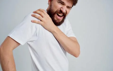 Man touching shoulder with hand dislocation discomfort white t-shirt Stock Photos