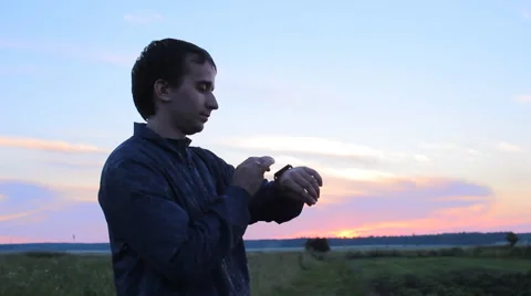 Man touching smart clock on the background of beautiful sunset sky Video stock 64777249