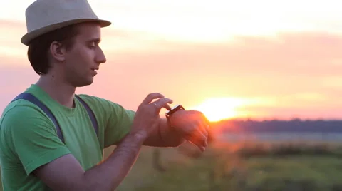 Man touching smart clock on the background of beautiful sunset sky Video stock 64777278