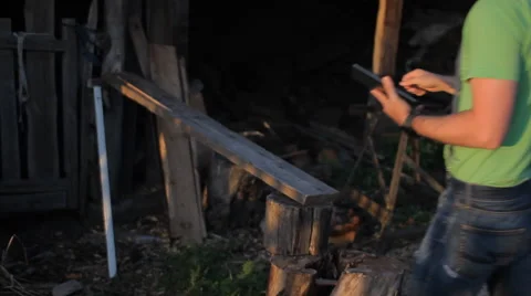 The man is touching the tablet at the sawmill. sunset time Video stock 64776849