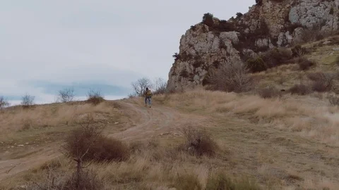 Man with tourist backpack is heading towards the mountain. Video in 4k Stock Footage 104743514