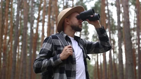 Man tourist with a backpack looks through binoculars while hiking in the forest Stock-Footage 149946602