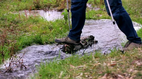 Man tourist with a backpack passes through a stream Stock Footage 56615055