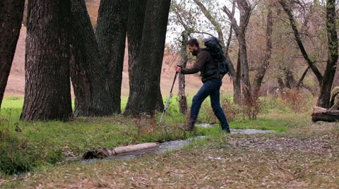 Man tourist with a backpack passes through a stream Stock Footage 56616100