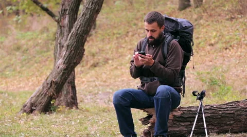 Man tourist with a backpack uses smartphone in the forest Stock Footage 56616062