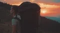The man with a tourist backpack walking on a mountain on a sunrise background 4k or 4k+ Resolution