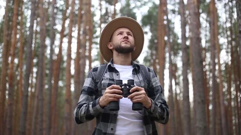 Man tourist with binoculars while hiking in the forest or mountains. Hiking Stock Footage 149946572