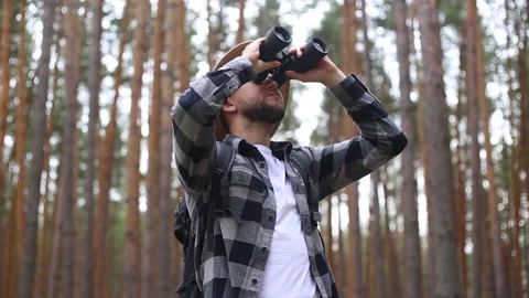 Man tourist with binoculars while hiking in the forest or mountains. Hiking Stock Footage 149946573