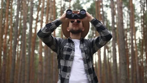 Man tourist with binoculars while hiking in the forest or mountains. Hiking Stock Footage 149946579