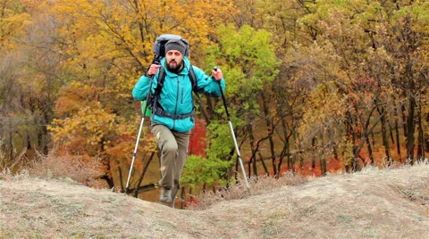Man tourist in a blue jacket with a backpack goes up the hill Stock Footage 56254981