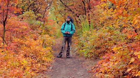 Man tourist in a blue jacket with a backpack looks around Stock Footage 56256857