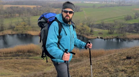 Man tourist in a blue jacket with a backpack looking around Stock Footage 62397696