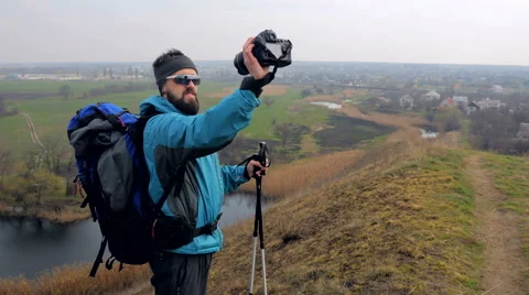 Man tourist in a blue jacket with a backpack makes selfie Stock Footage 62397720