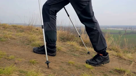 Man tourist in a blue jacket with a backpack and trekking poles walks outdoor Stock Footage 62398545