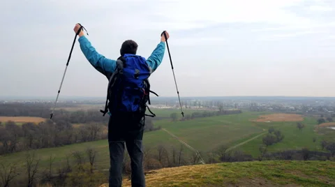 Man tourist in a blue jacket with a backpack enjoys his climbing Stock Footage 62398792