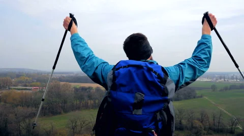 Man tourist in a blue jacket with a backpack enjoys his climbing Stock Footage 62398900