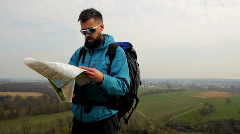 Man tourist in a blue jacket with a backpack looking on the map Stock Footage 62399173
