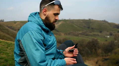 Man tourist in a blue jacket with a backpack looking on the compass Stock Footage 62399590