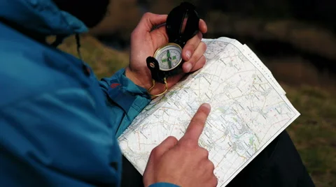 Man tourist in a blue jacket looking on the compass and map Stock Footage 62400073