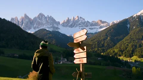 Man tourist looking at wooden pointer at the trail in Dolomites Alps near Santa Stock Footage 262993722