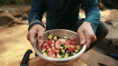 A man-tourist prepares a salad while hiking in nature Stock Footage 264141848