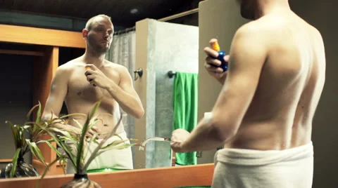 Man in towel applying sunscreen lotion on his arms in the bathroom at home HD Stock Footage 51770254