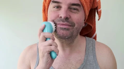 Man with towel on head using portable electric massager for making face massage. Stock Footage 129567064