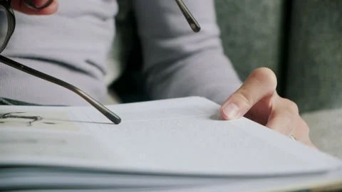 Man tracing text from book with tip of glasses frame Video stock 130639124