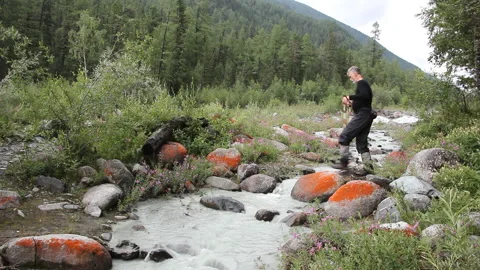 Man with tracking sticks  passing through the Akkem River, Altai Mountains Stock Footage 97259358