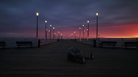 Man In Tracksuit and Protective Face Mask Stretching on a Seaside Pier at Dusk - Stock Footage 130729540