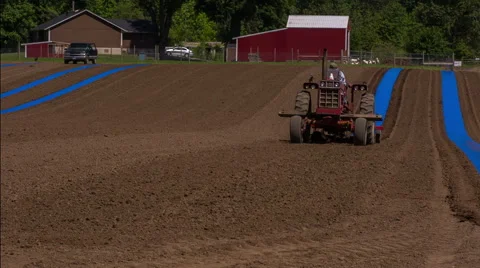Man on tractor laying blue strips in rows Stock Footage 44192350