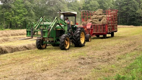 Man on tractor pulls a kick hay baler. Ambient sound Stock Footage