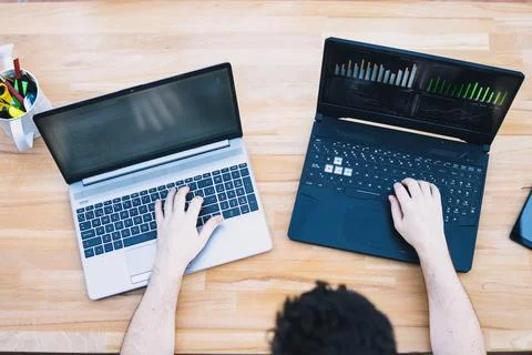 Man trading cryptocurrencies using two laptops Stock Photos