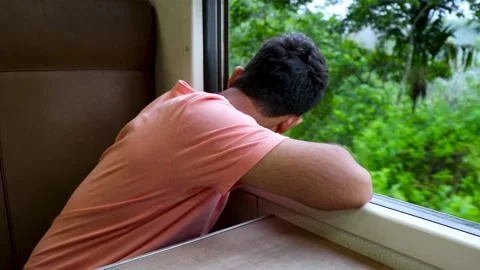 Man in a train sitting by a window, watching beauty of nature on mountain route Stock Footage 255544102