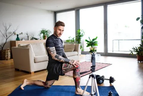 Man trainer doing online workout exercise indoors at home, using camera. 스톡 사진
