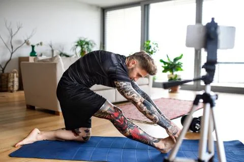 Man trainer doing online workout exercise indoors at home, using camera. 스톡 사진