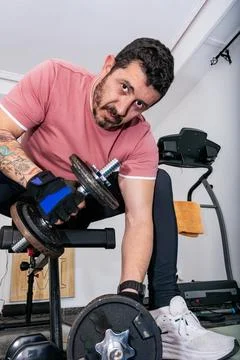 Man training biceps with adjustable dumbbell at home gym Stock Photos