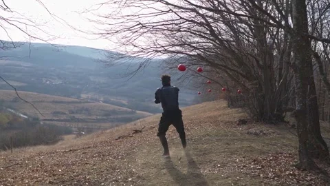 Man Training to Cut Red-Painted Oranges in the Forest Stock Footage 307849809