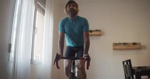 Man training hard with an exercise bike in his living room. Stock Footage 145908093