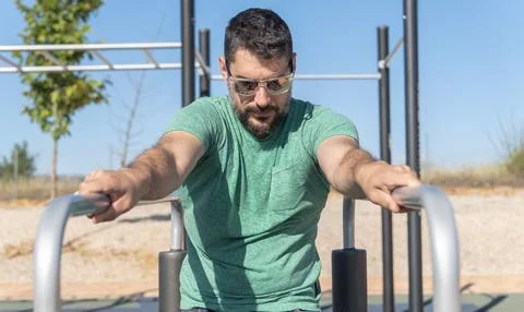 Man training his arms on parallel bars 스톡 사진