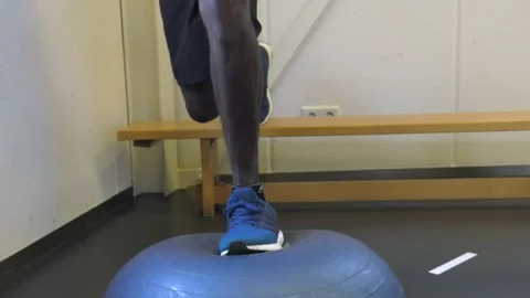 Man Training His Knee On An Exercise Ball With A Personal Coach Stock Footage 130676711
